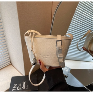 Gros plan sur le sac seau en cuir plissé blanc avec breloque cœur et bandoulière