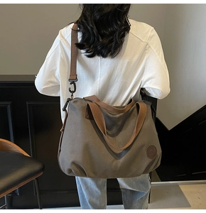 Detail view of large gray waterproof travel bag with brown straps and leather logo patch