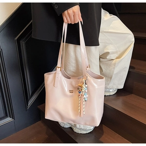Detail of light pink patent leather tote bag with glossy finish and tassel charm