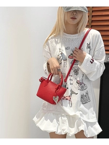 Mini sac seau en cuir rouge avec pendentif cœur argenté porté par un mannequin femme