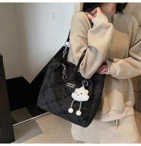 Close-up of black quilted star pattern tote bag with metal chain and plush charm
