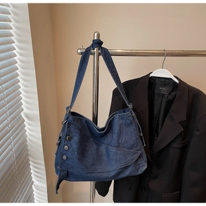 Detail of blue denim tote bag featuring adjustable knotted shoulder strap and metal buttons