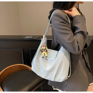 Light blue pleated hobo bag with wide strap and cute yellow doll pendant detail