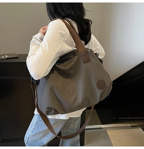 Detail of grey-green canvas tote bag with adjustable brown strap and side logo patch
