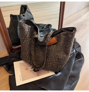 Close-up of leopard print canvas tote bag with orange leather tag on wooden floor