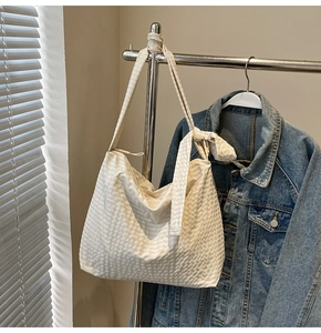 Detail of cream hobo bag with textured fabric, knotted strap and drawstring closure