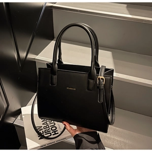 Macro detail of black leather tote bag with gold logo and metallic hardware accents