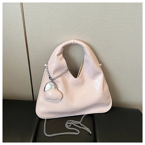 Detail of light pink glossy pleated handbag with silver chain and heart charm