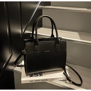 Detailed side view of a black structured tote bag with golden lettering on steps