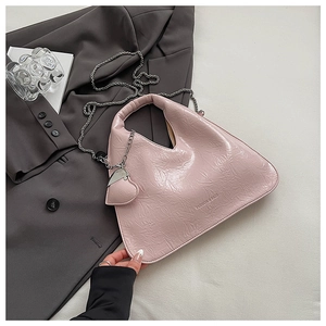 Detail of pink pleated chain bag with heart charm on a dark blazer background