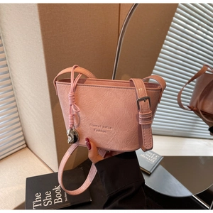 Gros plan sur un sac seau en cuir rose avec texture plissée et breloque coeur métal