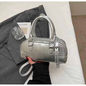 Silver cylinder handbag with metallic finish and top handles on a white bedding background