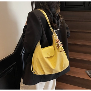 Detail view of large yellow hobo bag in nylon fabric with side flap and pearl charm