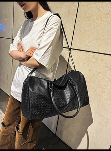 Detail of black houndstooth embossed tote bag featuring sturdy handles and texture