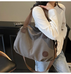 Detail of grey waterproof gym bag with brown handles worn by model in minimalist setting