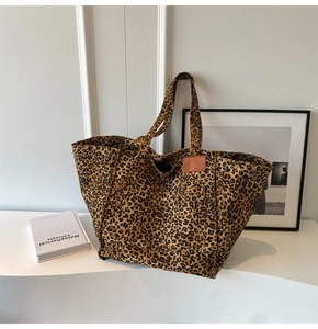 Detailed view of leopard print canvas tote bag with leather tag and metal rivet accents