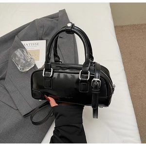 Detailed close-up of a black patent leather bowling bag with silver hardware and logo detail