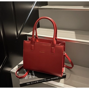 Detail view of red leather handbag with gold branding on modern interior stairs