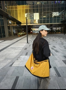 Detailed outdoor shot of a yellow nylon tote bag with a black base and adjustable strap