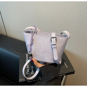 Détail du sac seau violet clair avec texture plissée et pendentif sphérique argenté