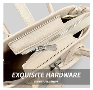 Close-up of silver metal zipper and textured off-white pebble leather bucket handbag