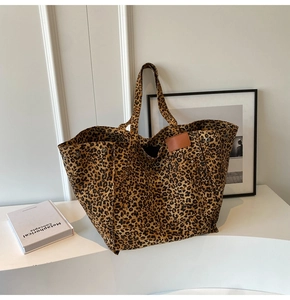 Detail of leopard print canvas tote bag featuring metal rivets and leather logo patch