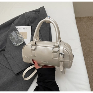 Detail of beige bowling bag featuring silver hardware and adjustable shoulder strap
