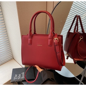 Macro detail of wine red leather tote bag with gold logo and elegant shoulder strap