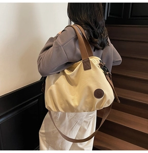 Detail of water-resistant travel tote bag showing side leather logo and adjustable strap