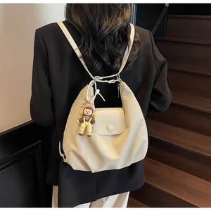 Detail of cream canvas tote bag showing adjustable strap and cute doll pendant ornament