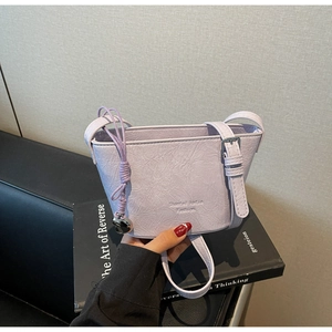 Détail du sac seau lavande avec texture froissée, logo et pendentif en cœur