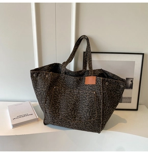 Close-up of leopard print canvas tote bag with front pocket, metal rivets and leather patch