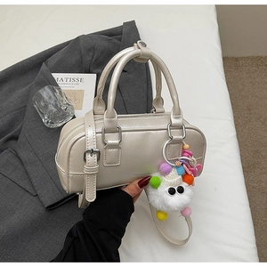Chic pearlescent white Boston bag with colorful plush monster charm and smooth PU texture