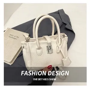 Detail shot of cream lychee pattern leather bucket bag with silver metal swivel lock hardware