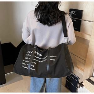 Close-up of black canvas travel tote with adjustable strap and branding print
