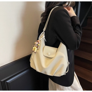 Detail of cream canvas tote bag featuring soft PU leather texture and magnetic flap closure