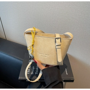 Détail du sac seau crème montrant la texture PU plissée et la corde jaune avec breloque cœur