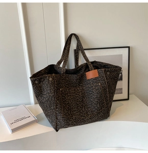 Detail of leopard print canvas tote bag featuring metal rivets and large front pocket