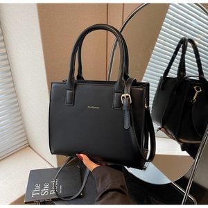 Close-up of black faux leather tote with gold logo and adjustable shoulder strap