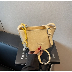 Détail du sac seau crème avec texture plissée et pendentif en forme de cœur argenté