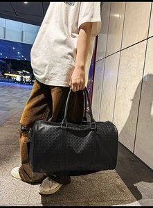 Detail view of black embossed leather travel tote bag with durable handles and metal rings