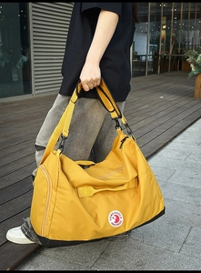 Detail view of bright yellow nylon tote bag with reinforced handles and side zipper pocket