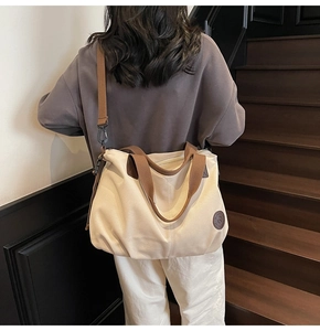 Macro view of large off-white canvas tote bag with adjustable brown shoulder straps