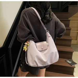 Detail view of large mauve canvas tote bag featuring pleated design and cute doll charm