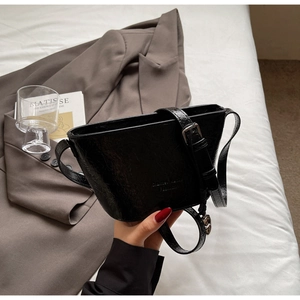 Détail du sac seau noir en cuir craquelé avec une bandoulière réglable et élégante