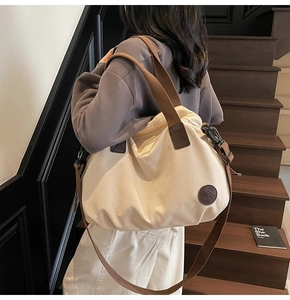 Detail of cream canvas tote bag with brown straps and logo on wooden stairs background