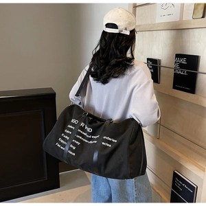 Detailed view of black canvas travel bag with white quote print and adjustable strap