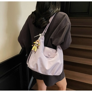 Detail view of lavender faux leather shoulder bag with cute cartoon doll charm