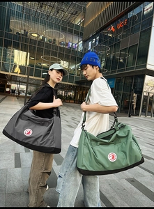 Detail of high-capacity nylon tote bags in grey and green with wide straps and metal buckles