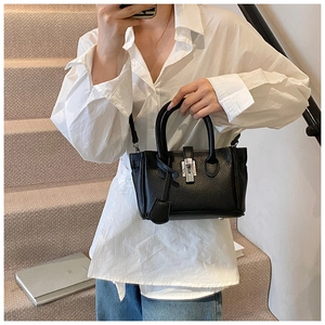 Detail of black lychee grain leather bucket bag featuring a silver twist-lock and shoulder strap